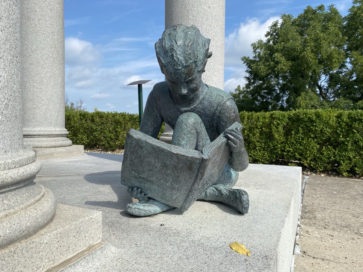 Statue of a child reading a book at the James Whitcomb Riley tomb