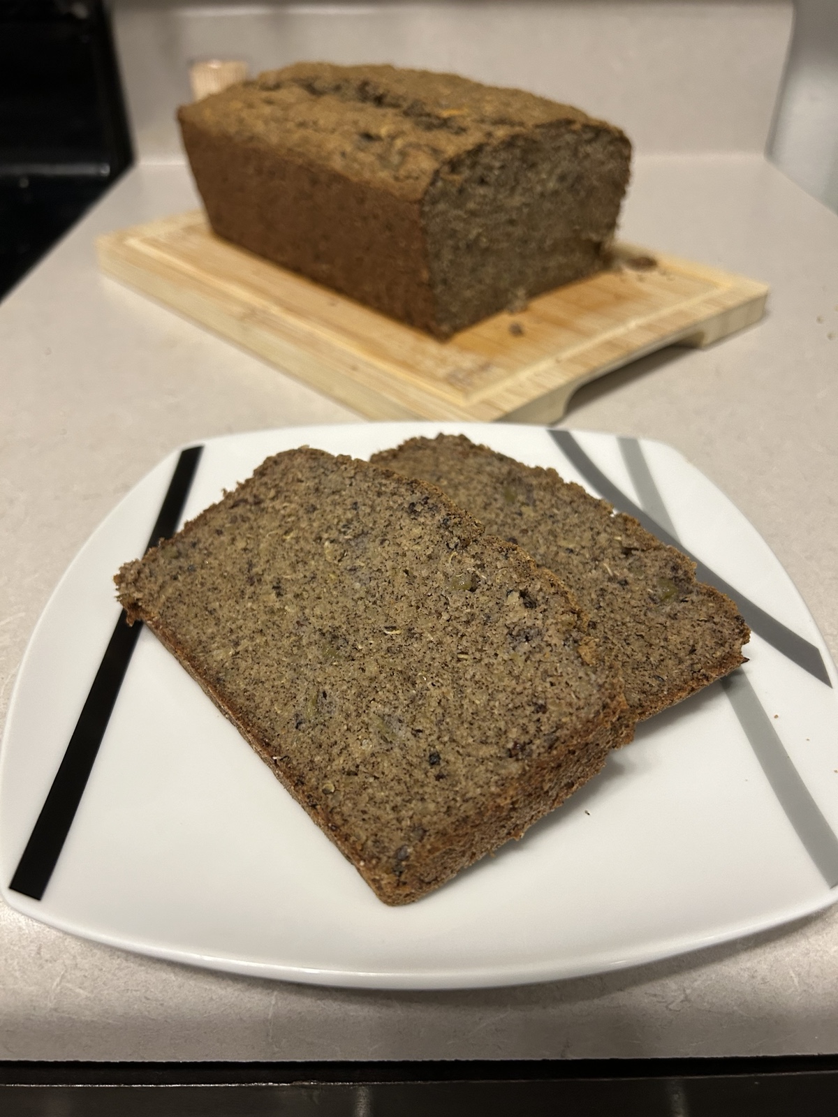 Slices of bread on a plate with a loaf of bread in the background on a cutting board.