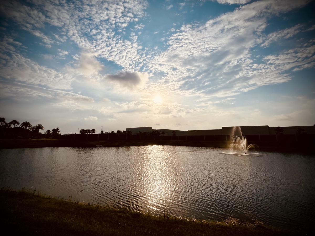 Sunrise over a building and pond