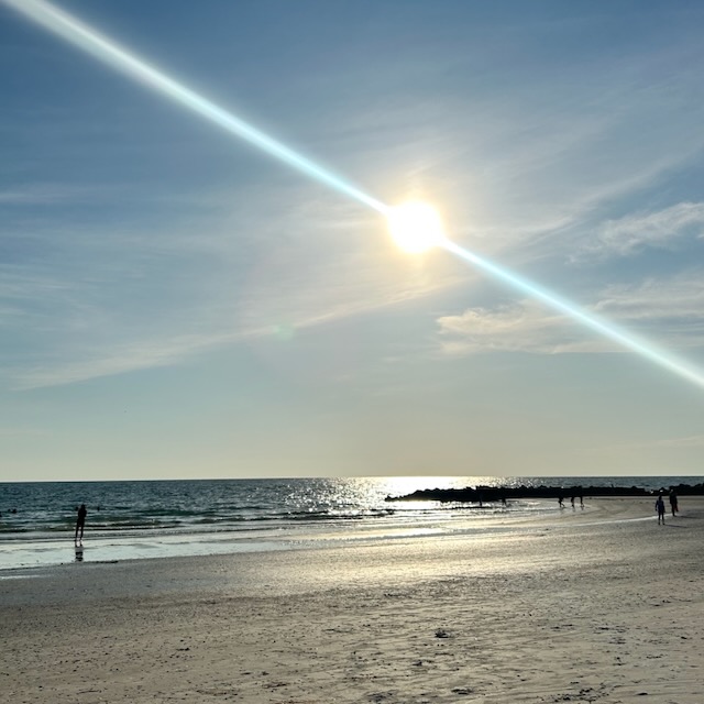 Sun setting over the ocean with a beach in the foreground