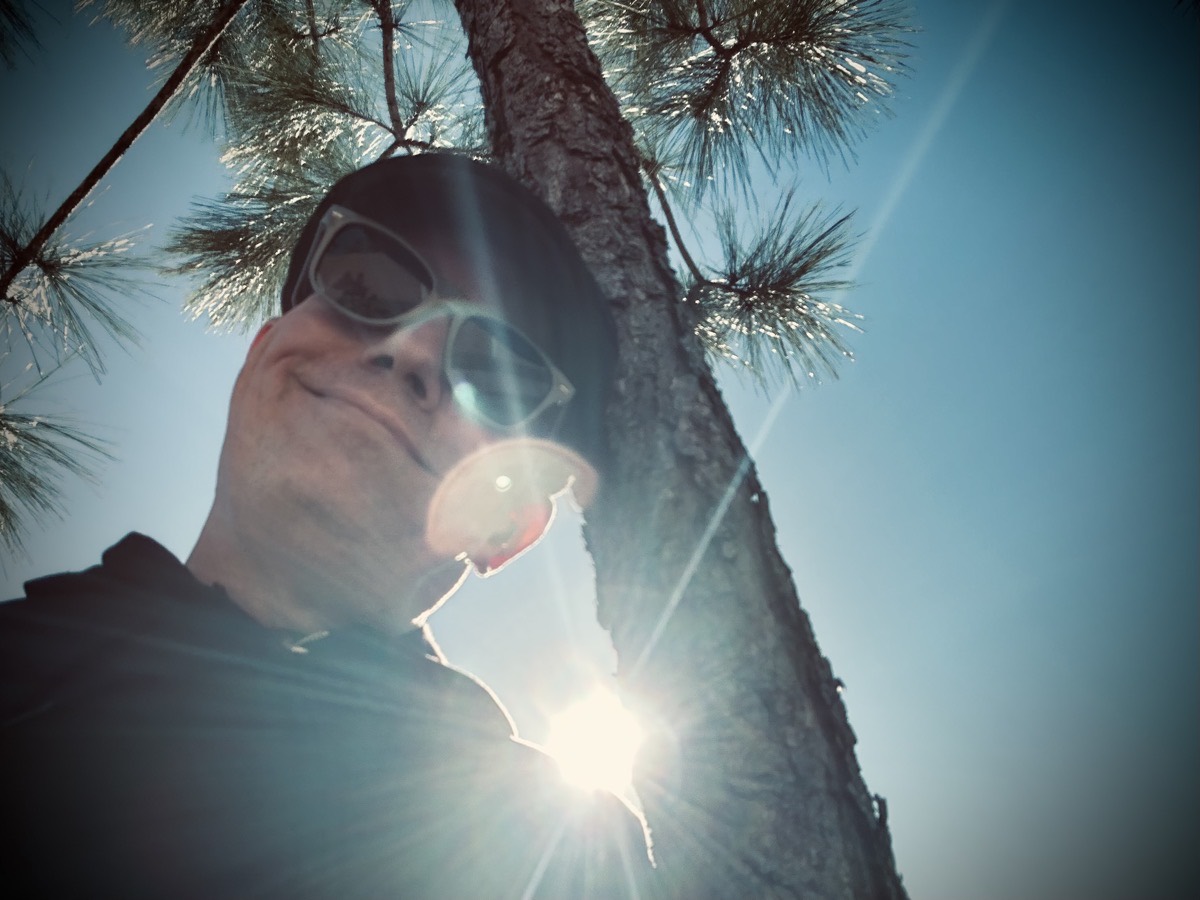 Selfie leaning against a tree with the sun glaring over my shoulder