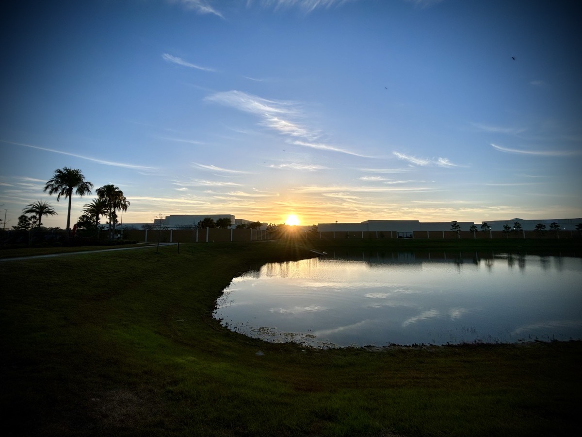 Sunrise over a building and pond