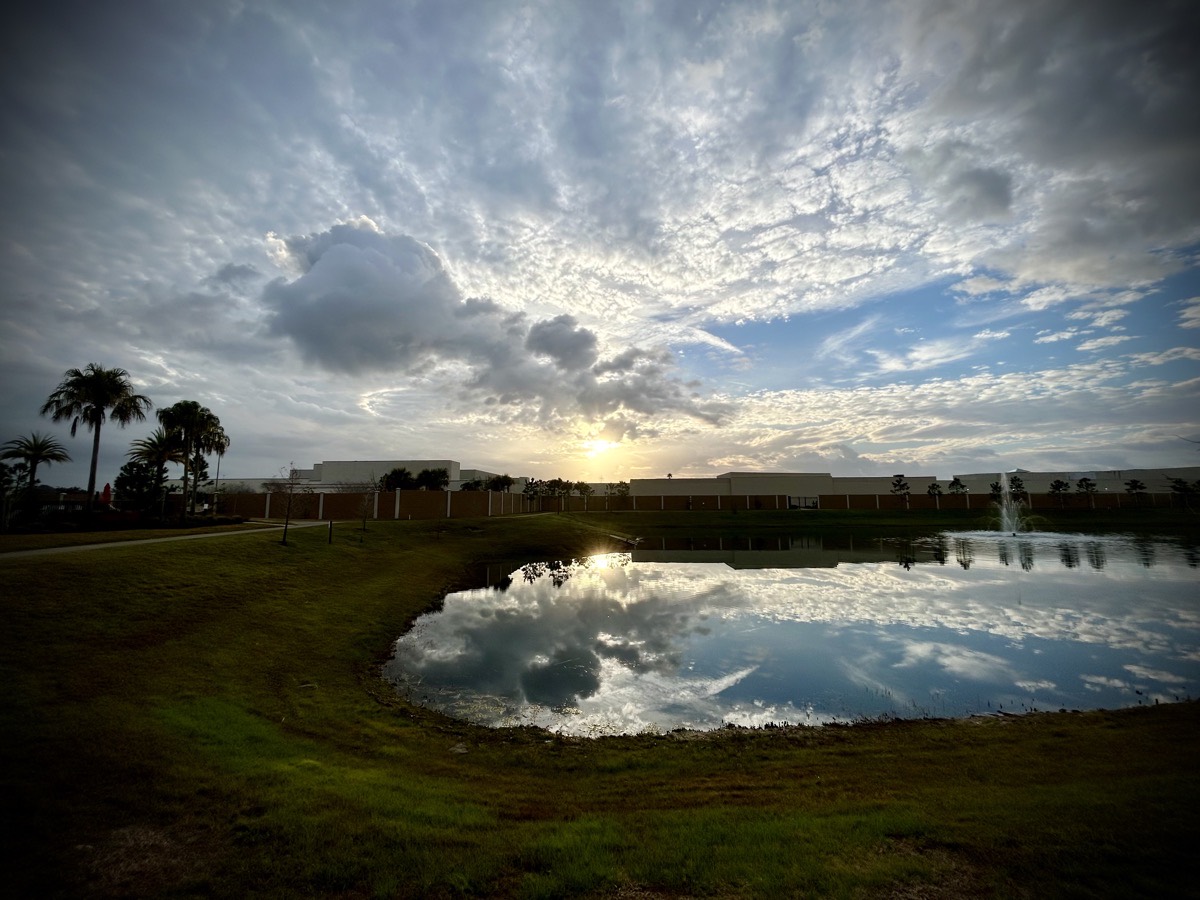 Sunrise over a building and pond