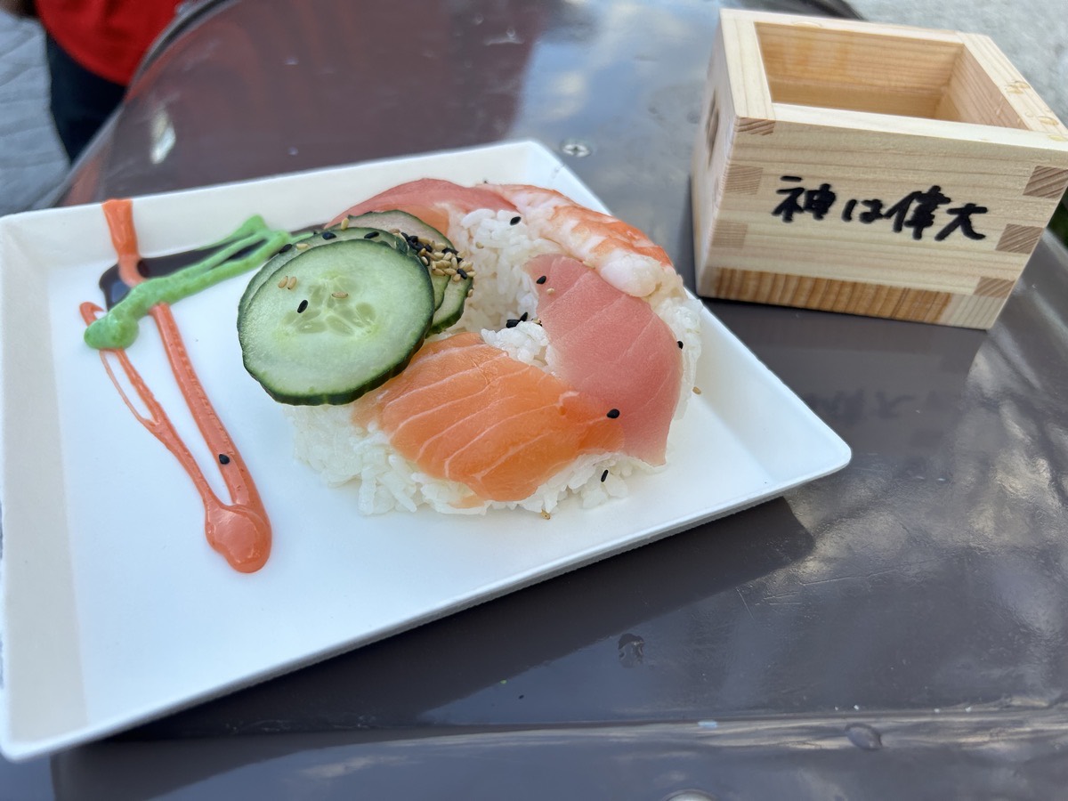 Sushi doughnut and sake. The sake cup says "God is great" in Japanese.