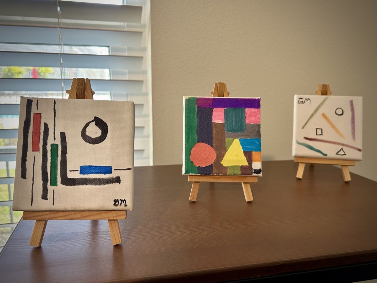 3 mini paintings on mini easels on a shelf