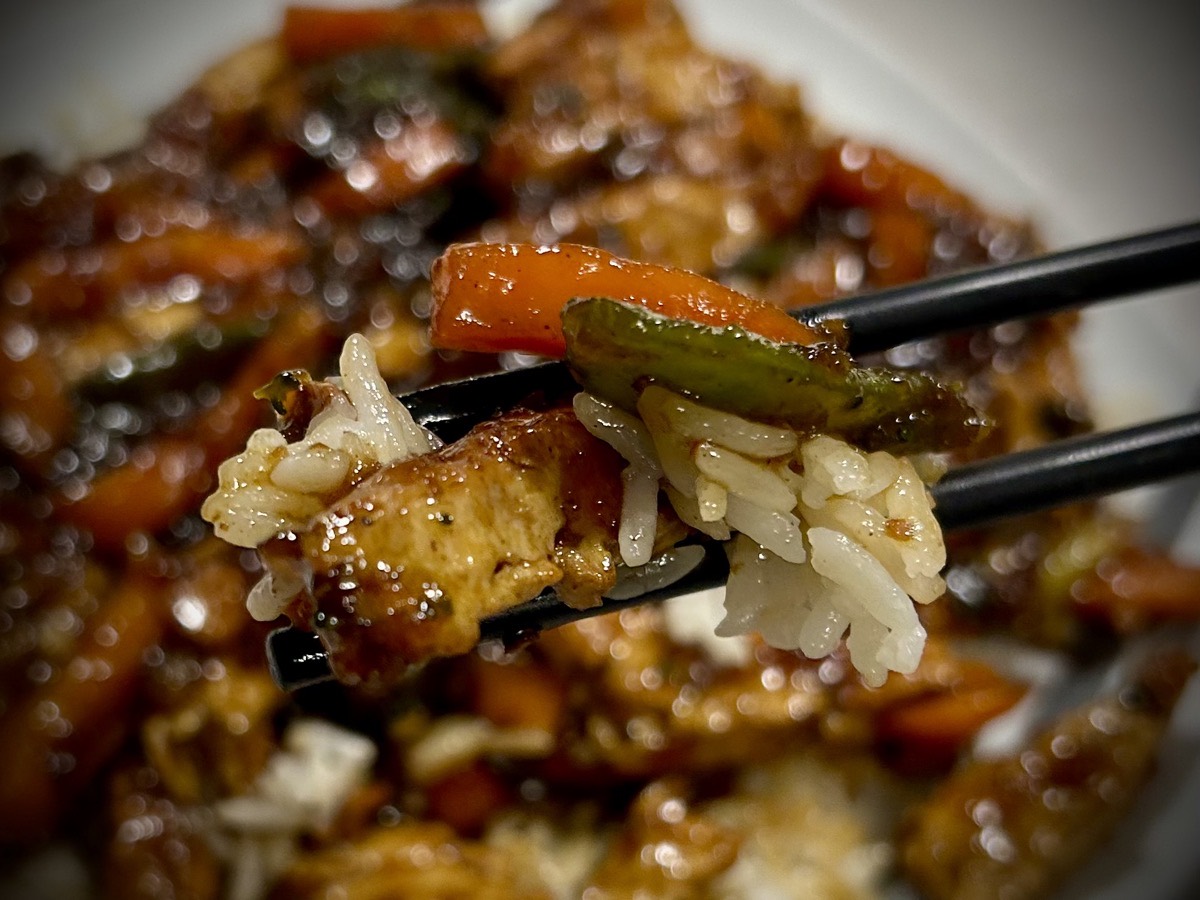 Close up of plant-based "chicken" stir fry in chopsticks