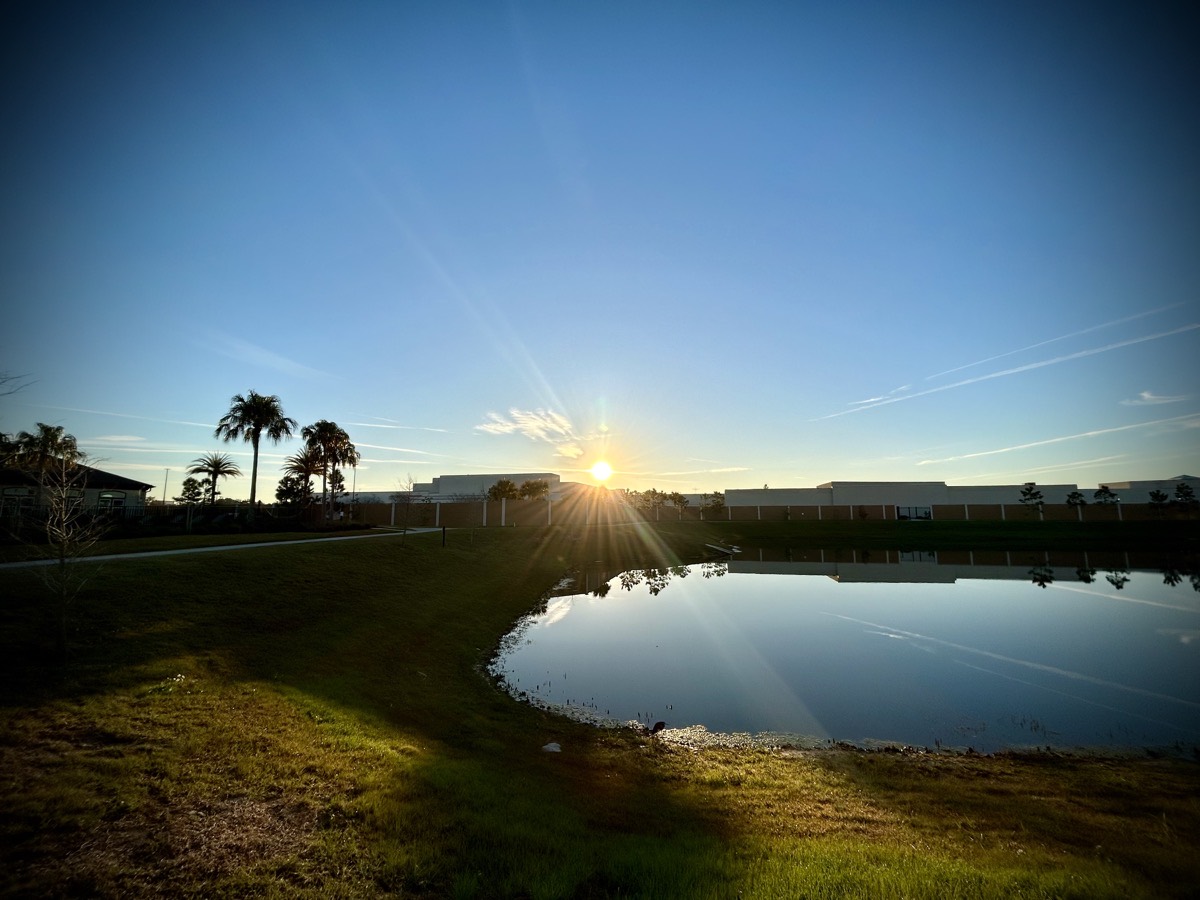 Sunrise over a building and pond