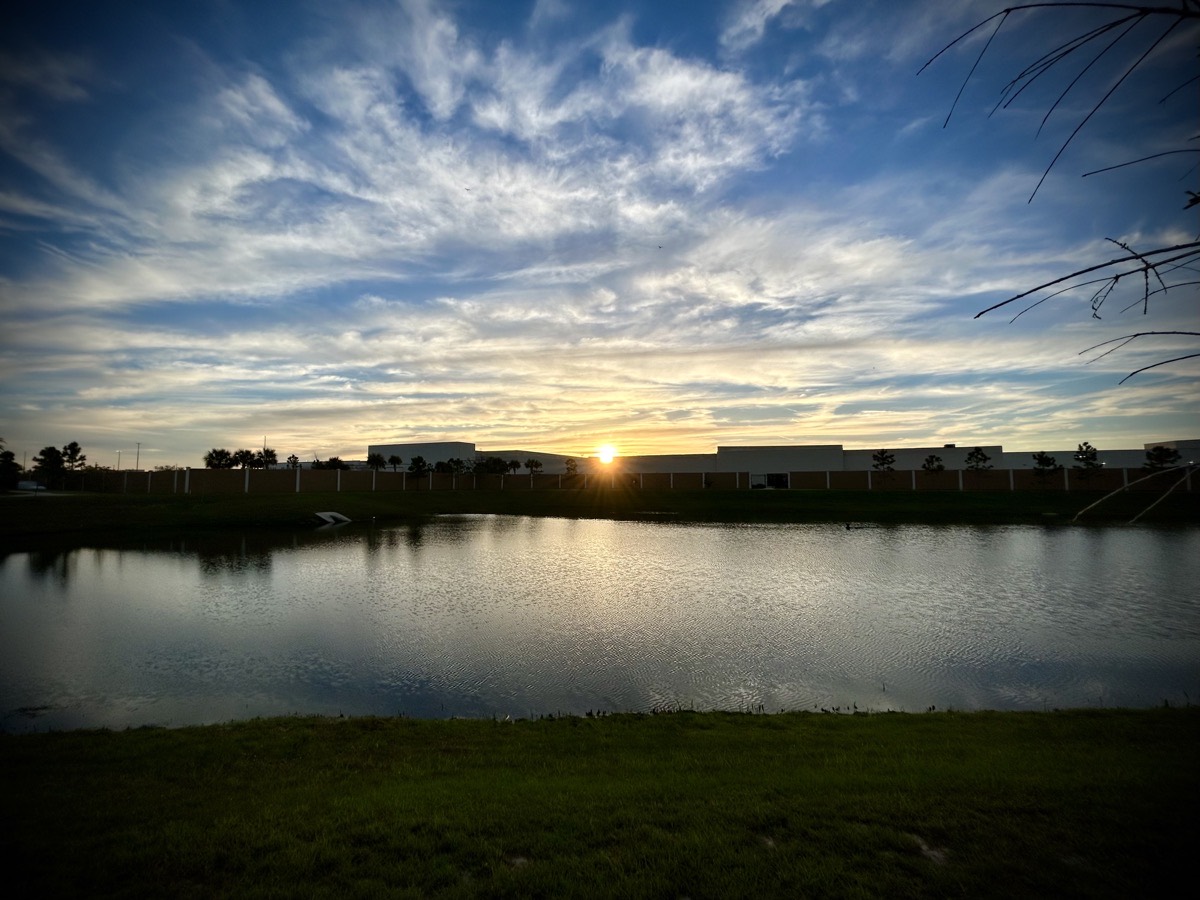 Sunrise over a building and pond