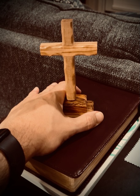 Hand holding a cross on a Bible