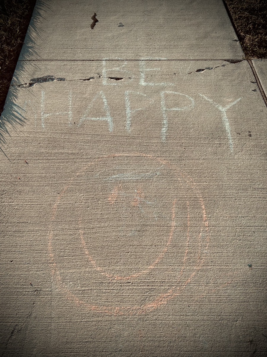 Chalk drawing with a smiling face and the words says be happy 